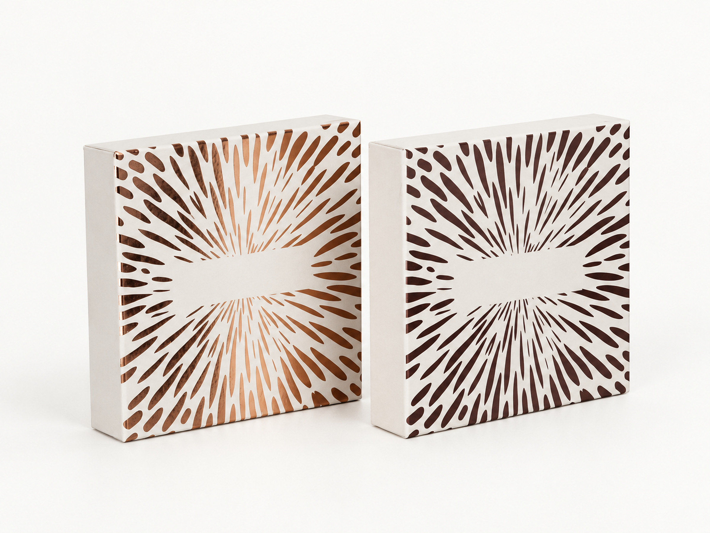 Two white gift boxes with radial dash patterns in metallic and dark finishes, standing side by side. Supplementary reference only; product identity, sizes and availability require confirmation.