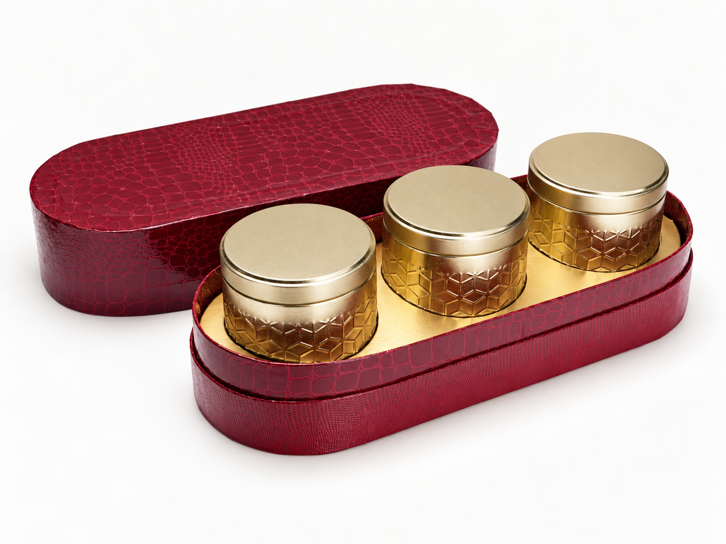 Open burgundy oval hamper box with three gold-lidded display jars and its matching textured lid behind.