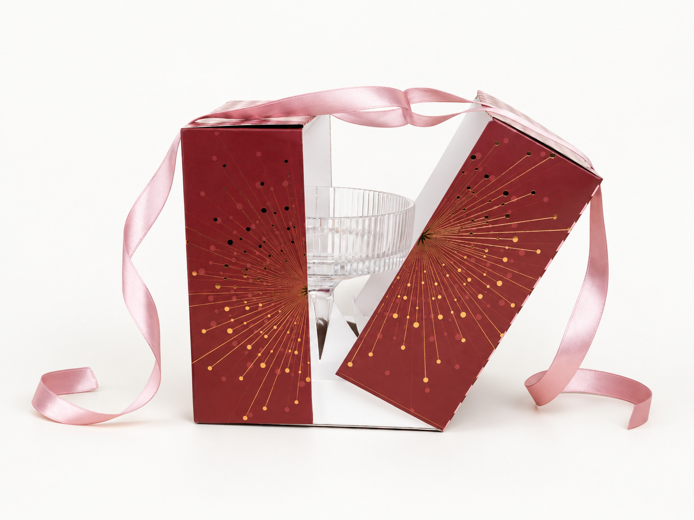 Partly open burgundy starburst gift box with pale pink ribbons and a stemmed glass shown inside for display.