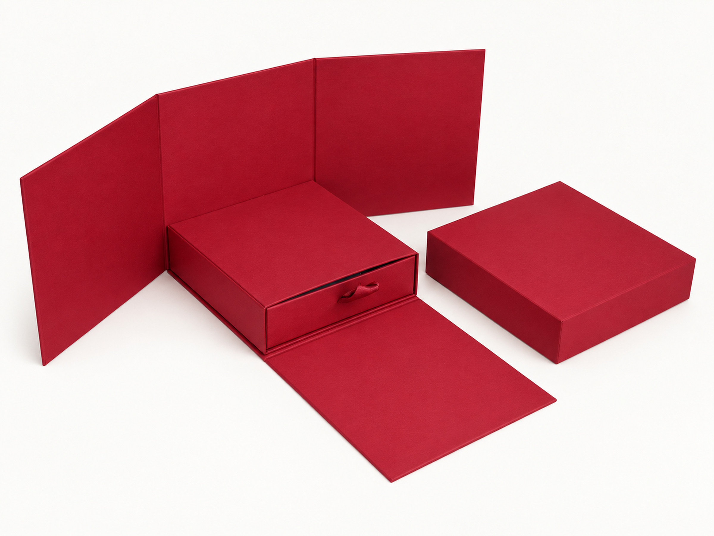 Burgundy gift box with wraparound panels opened, a ribbon-pull drawer and a separate lid beside it.