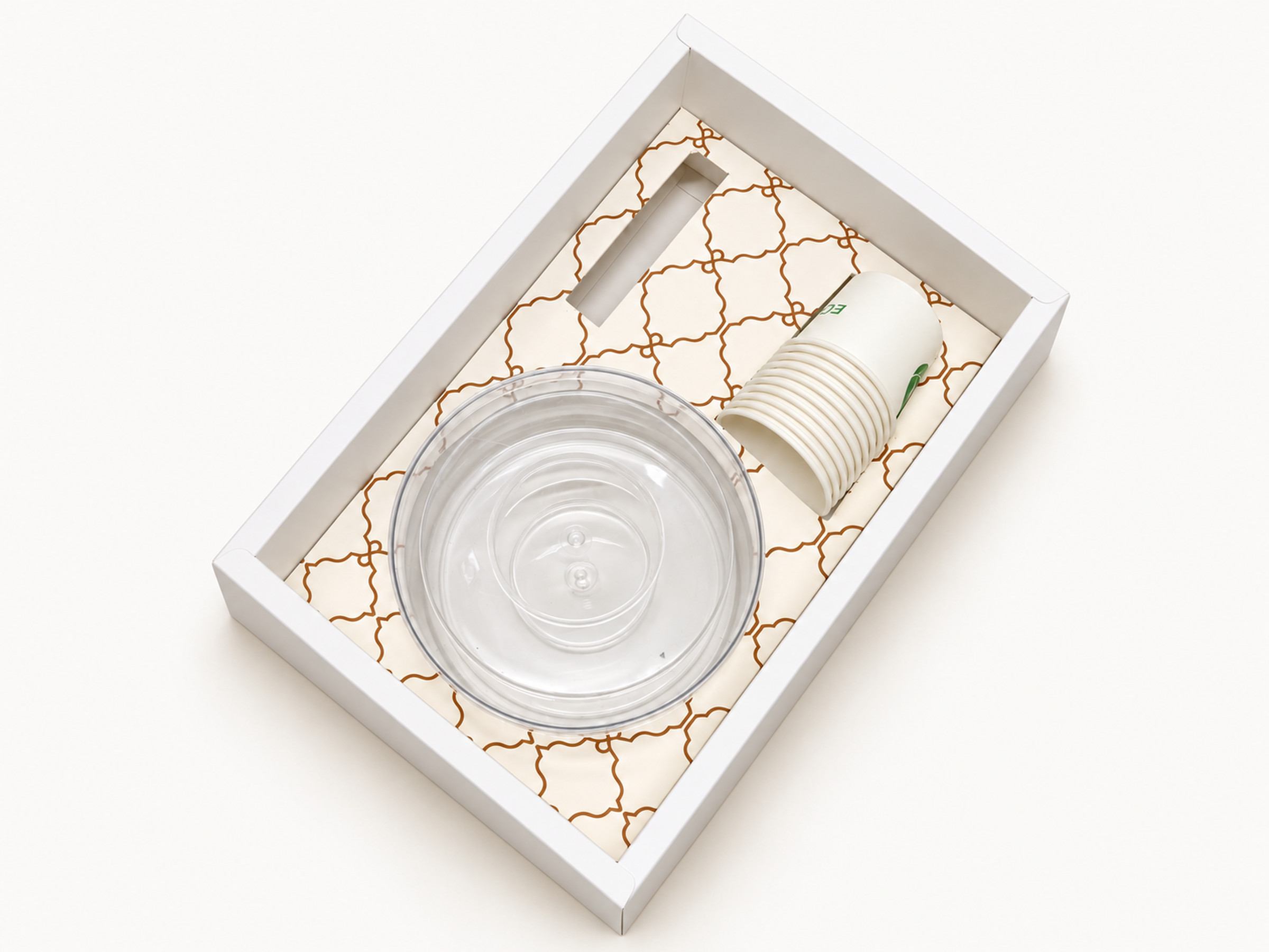 Open white gift tray with a gold-coloured lattice insert, stacked paper cups and a clear round container.