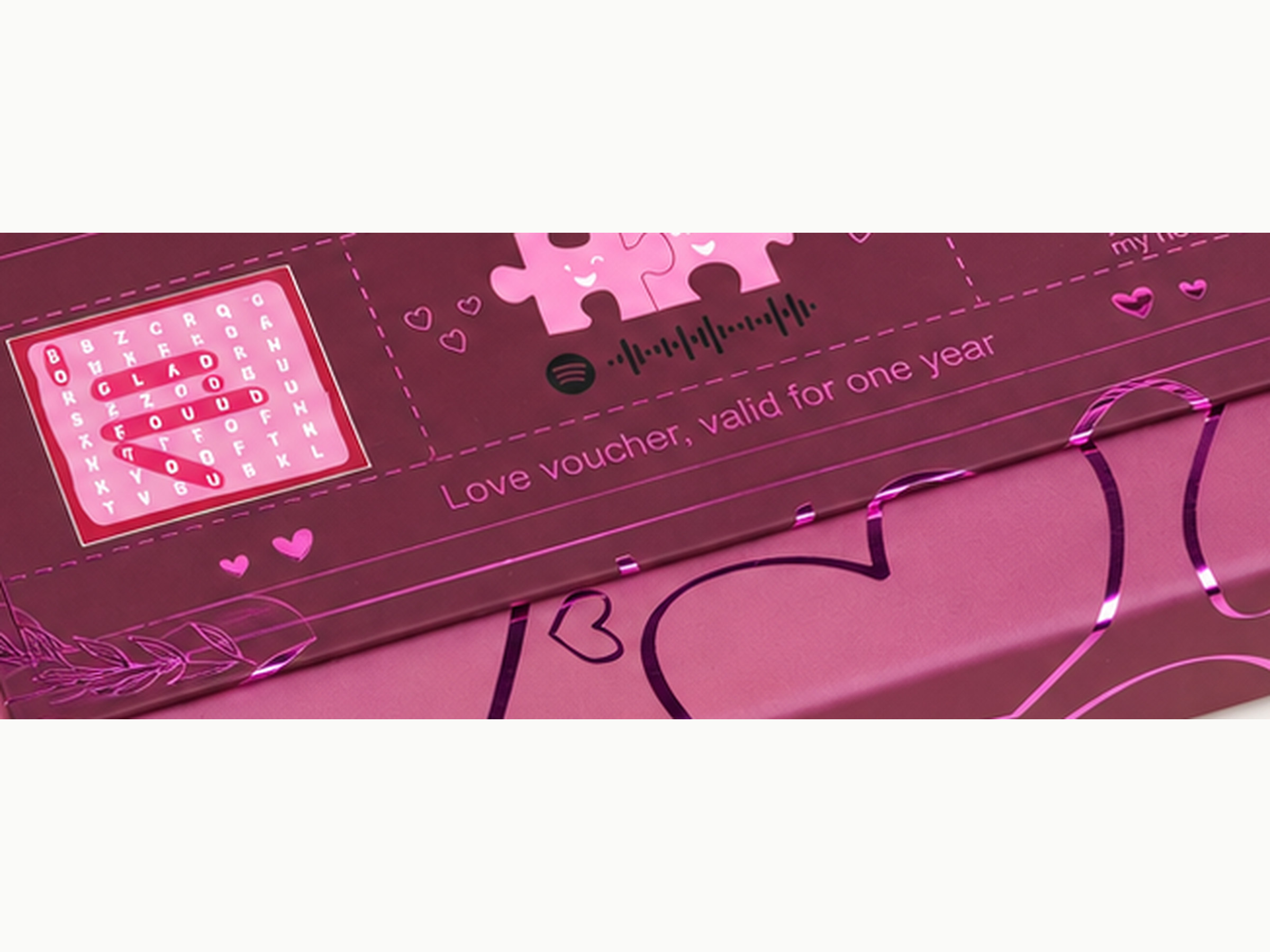 Close-up of the burgundy Love Notes gift box lid showing printed hearts and love-note artwork, shown in a square detail crop.