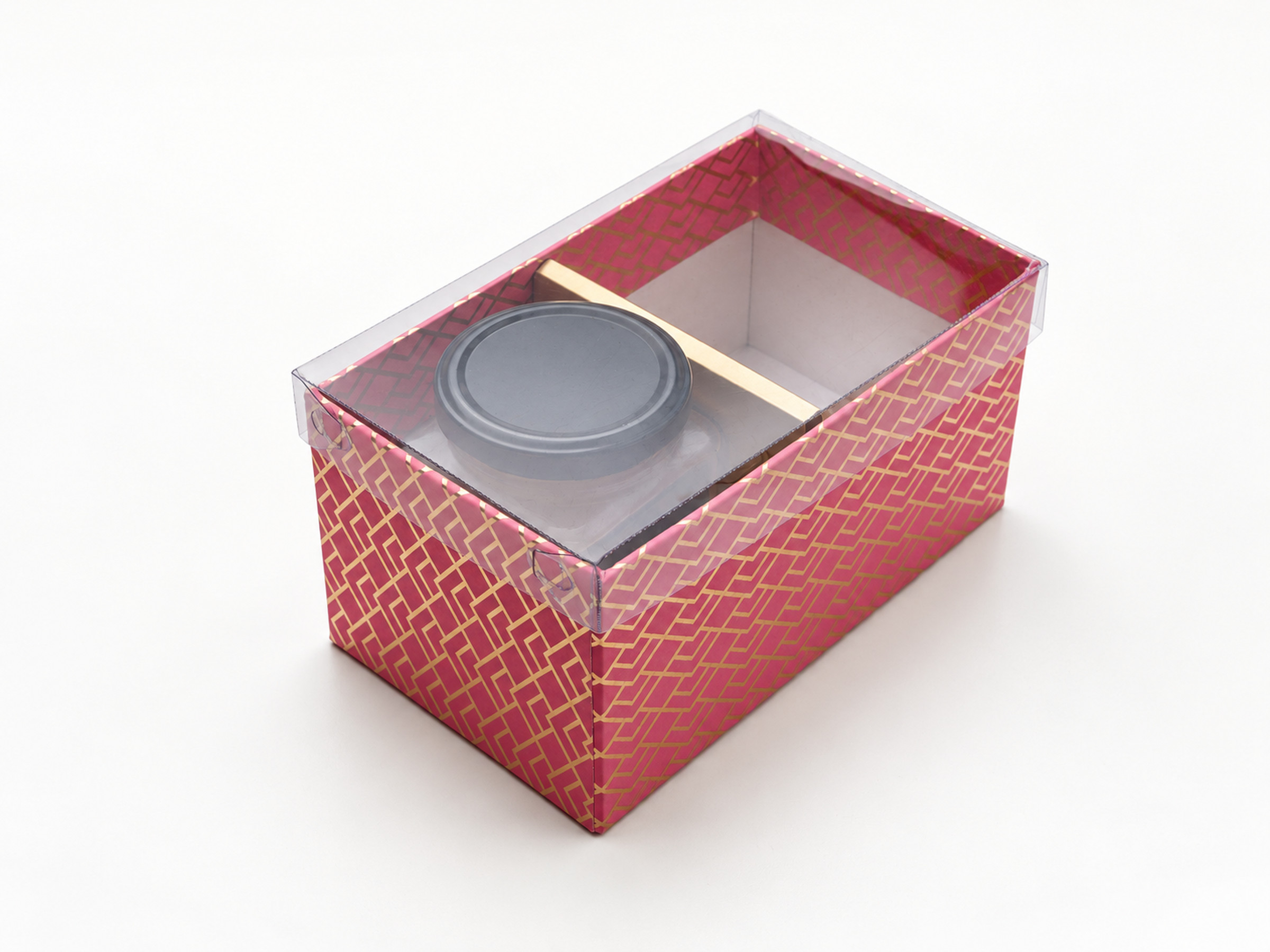 Pink geometric two-compartment jar hamper box under a clear lid, with a gold divider and one jar visible inside.